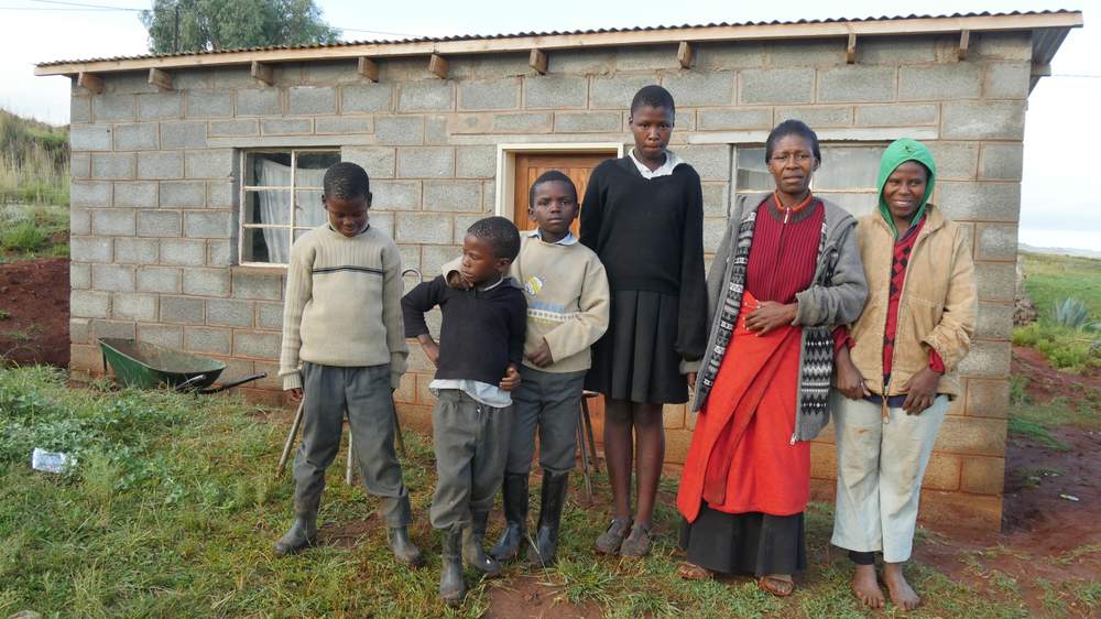 Masease Masolanka and her family in front of their new home.