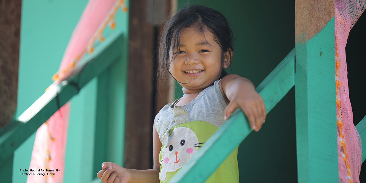 Young Cambodian girl smiling on her brightly colored stairs.