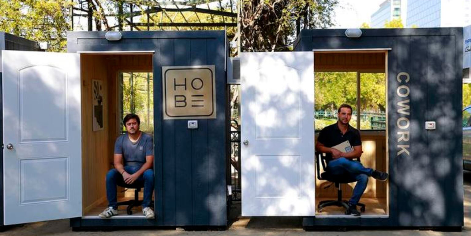 Photo of two men from startup HOBE sitting inside small structures.