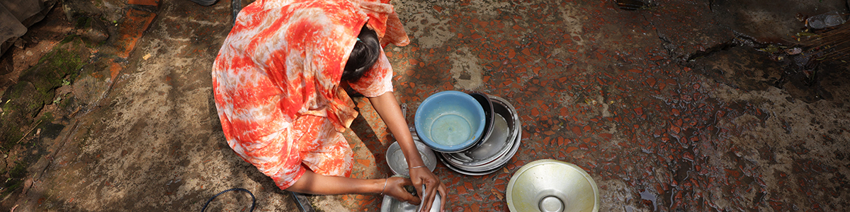 A woman washing dishes outside.