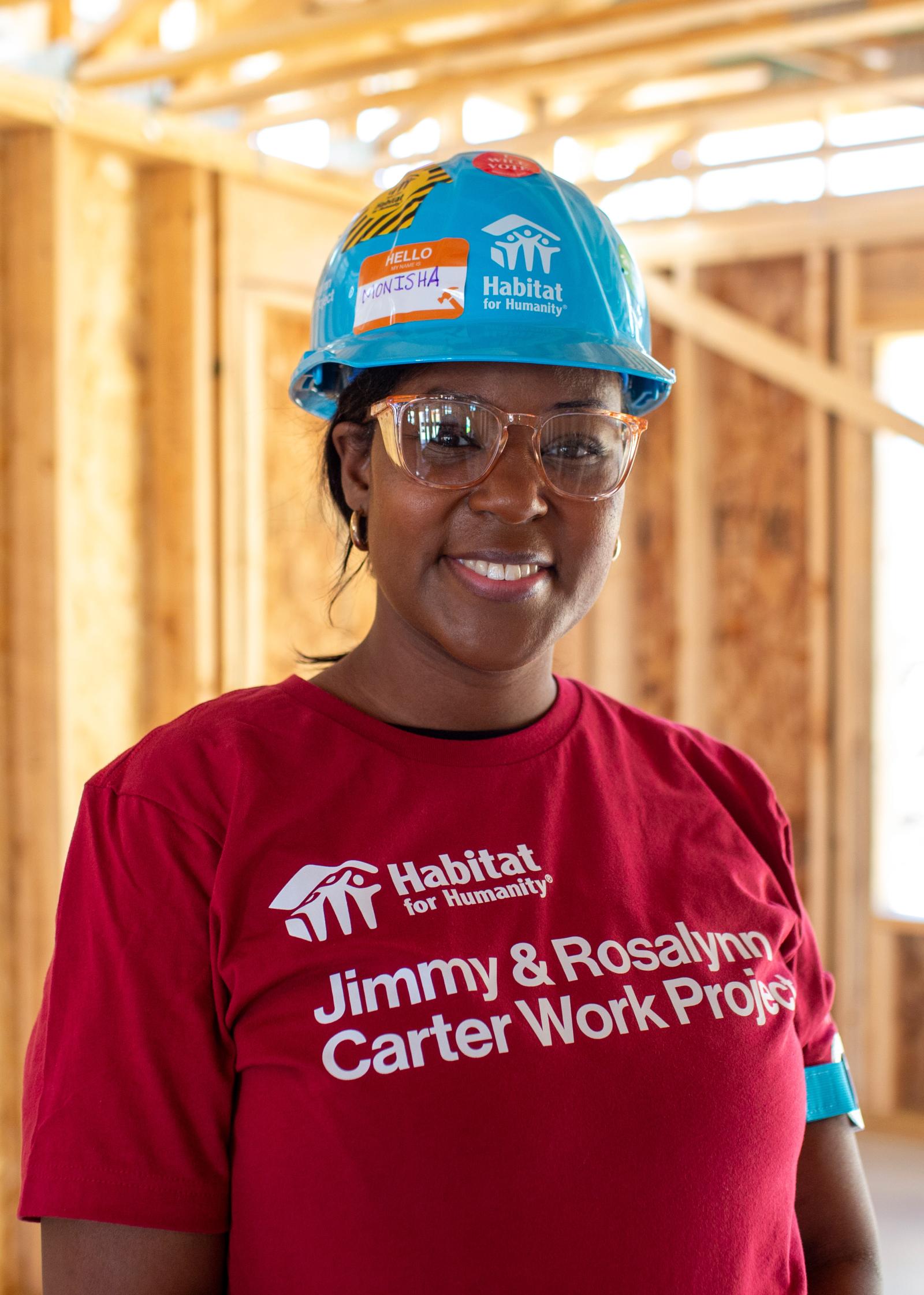 Monisha on the build site with a blue hard hat.