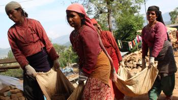 Photo: women carrying bricks together in a rug