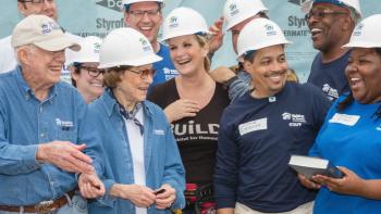 President and Mrs. Carter smiling with a group of Habitat volunteers and a Habitat homeowner.