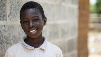 young Zambian boy smiling in front of his Habitat home.