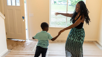 Homeowner and child dancing in living room.