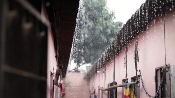 Photo of raindrops falling off a roof of a home in an informal settlement.