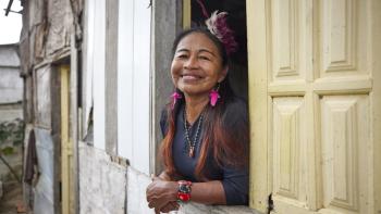 A homeowner leaning out of the window of her home and smiling.