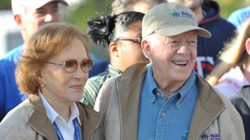 President Carter smiling wearing a Habitat hat with Rosalynn Carter by his side.