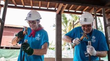 Two Global Village volunteers hammering a piece of wood during construction..