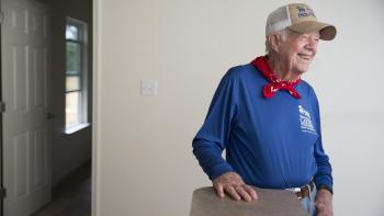 A smiling President Carter standing in a Habitat house