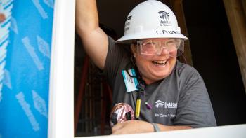 Woman in a hardhat smiling while volunteering on a build site