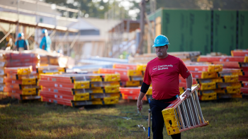 Volunteer carrying ladder.