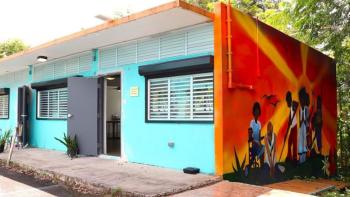 A small building with a bright orange mural painted on the side serves as a solar-powered "energy hub" for the community.