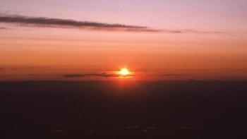 Sunrise breaking over horizon with orange and pink sky