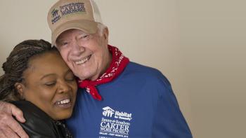 President Carter smiling with his arm around a Habitat homeowner woman