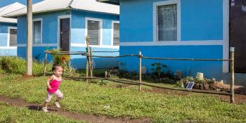 child running in front of blue house