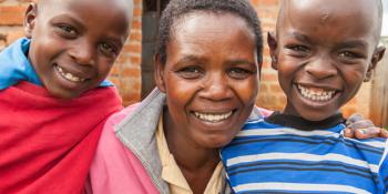 photo: a woman and two boys in front of a new house, Kenya