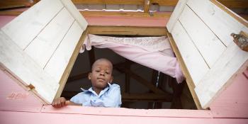 a boy looking from a window of his new home