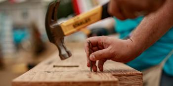 Volunteer hammers a nail into wood.