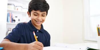 A boy sits at his desk completing homework.