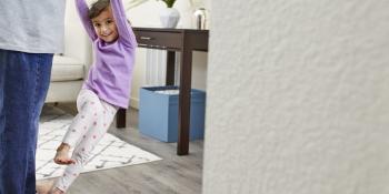 Little girl dances on father’s feet in the living room.  