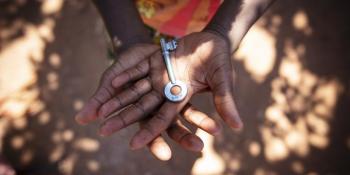 A young girl, who lives in a Habitat for Humanity Zambia home with her mother and her cousin, holds the key to her front door.