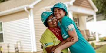 Habitat homeowner embraces volunteer outside her new home.