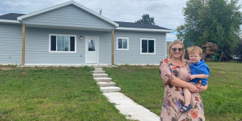 Teelyn and her 2-year-old son Isaiah stand in front of their Habitat home in Buhl, Minnesota.