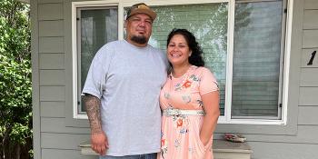 Husband and wife pose together in front of their Habitat home.