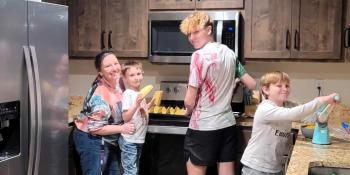 Mother and three sons smiling and cooking together in the kitchen of their Habitat home