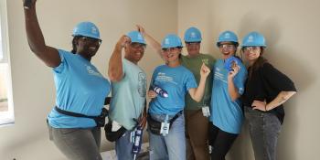 Group of Habitat volunteers standing inside a build house and smiling.