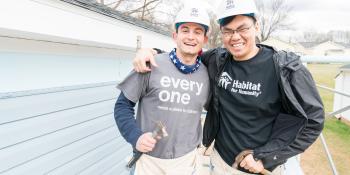 Two Collegiate Challenge volunteers stand together on a build site.