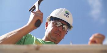 shot from below as volunteer hammers a nail