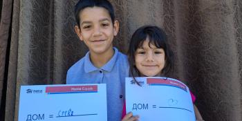 Children smiling holding a sign