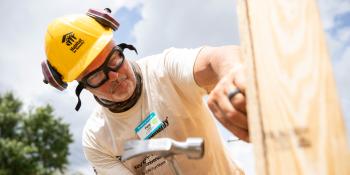 A volunteer hammers on a build site.