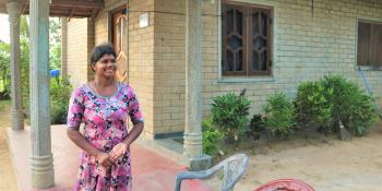 Thushanthini in a floral dress outside her home.