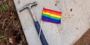 A hammer and a small pride flag laying side-by-side.