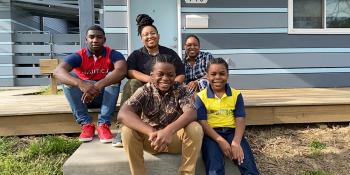 Star and her family of five sitting in front of their blue Habitat home.