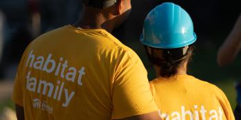 A couple hugging in their Habitat T-shirts, back to the camera.