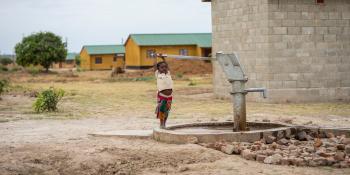 A young boy pulls a lever on a water kiosk.