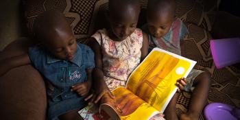 Photo: children reading a book on a sofa at home