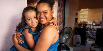 Mother hugging her young daughter in their home.