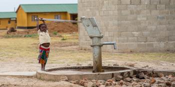 child pulling communal water well lever.