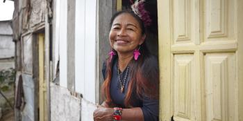 A homeowner leaning out of the window of her home and smiling.