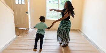 A woman dancing with her young son in their new house.