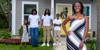 Smiling family of five standing in front of their new home