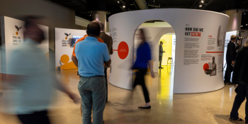 People walking around and reading displays in an interactive exhibit set up in an open area 