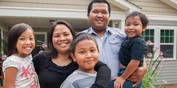 Familia de cinco personas sonriendo frente a la casa.