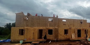 Wide shot of Habitat build site with Team Depot volunteers working on framing multiple houses