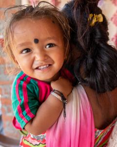 A happy child in his mother's arms smiles up at the camera.